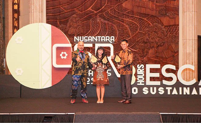 Three people are standing on a stage, posing for a photo. Two men and a woman are holding trophies. AI generated content