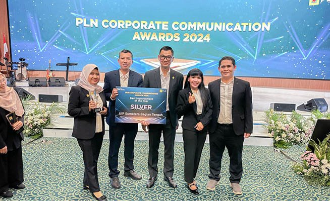 Four people pose for a picture in front of a sign that says “PLN Corporate Communication Awards 2024". AI generated content