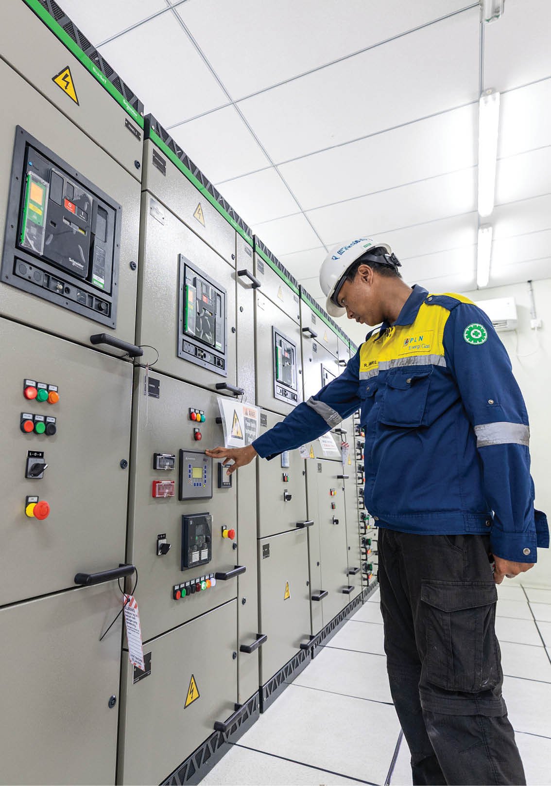 A man in a blue and yellow jacket is looking at a control panel. AI generated content